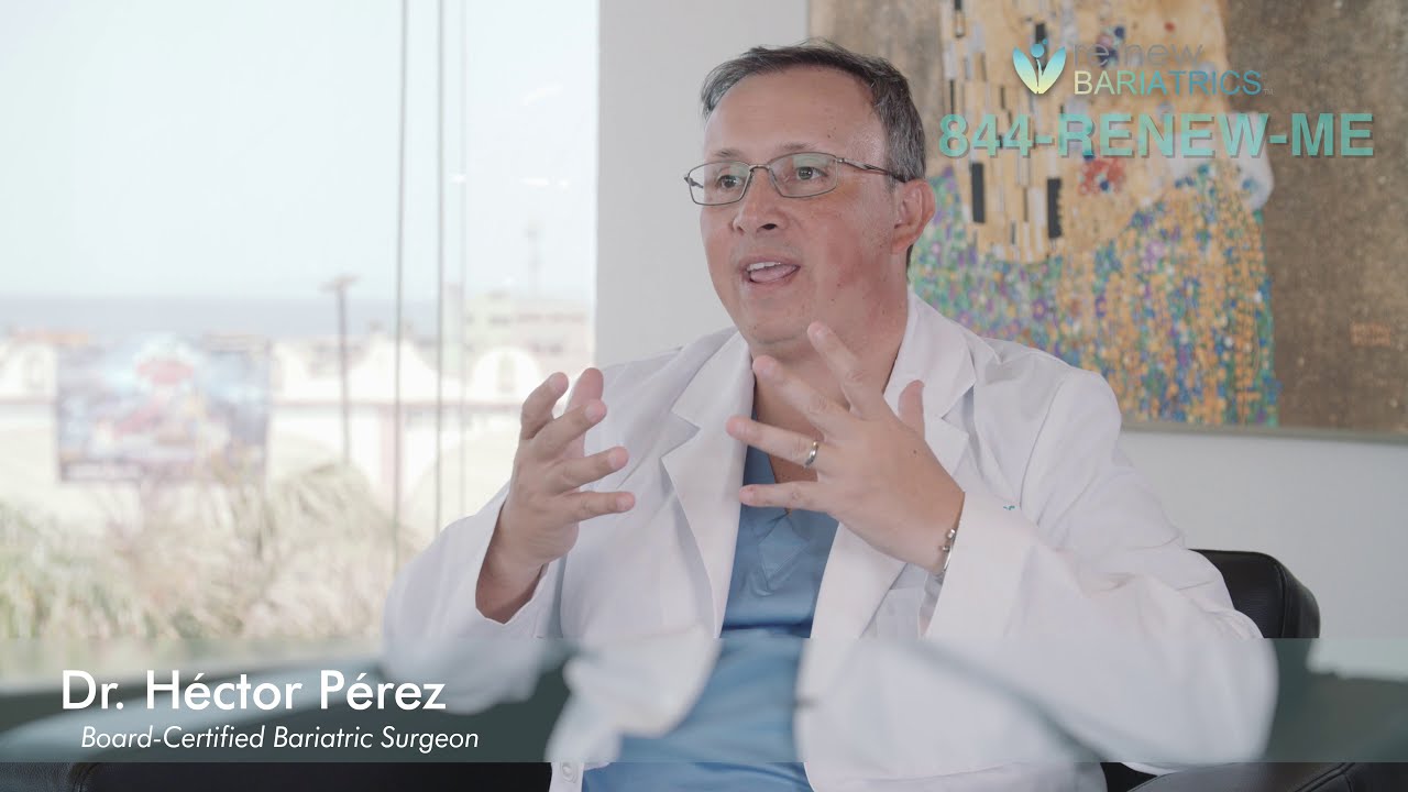 A man in a lab coat is speaking to the camera from home.