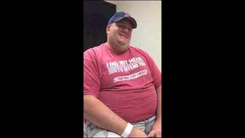 In a room, a man wearing a red shirt shares his successful gastric sleeve journey.